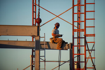 Iron worker wearing a hard hat and sitting on a steel beam