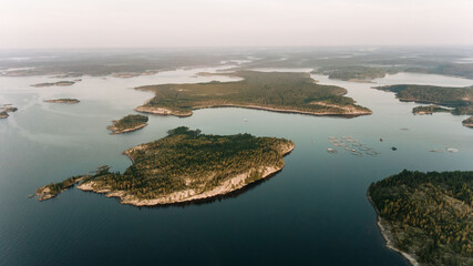 The soft light of dusk settles over a sprawling archipelago, where fish farms dot the tranquil...