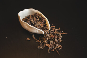 a white bowl filled with dried tea leaves on a black surface