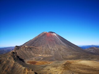 Volcano with a red crater and people standing nearby: Tongariro National Park, New Zealand © Wirestock