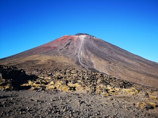 a volcano with red and green soil on a clear day