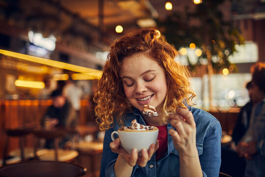 Happy woman enjoying hot chocolate in a cafe