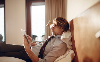 Mature businessman using a tablet while in a hotel room