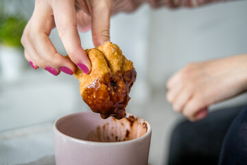  Detail of a Female Hand Dipping Fried Buñuelo in Hot Chocolate. Typical Valencian Food in Fallas