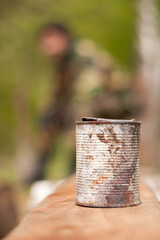 Rusty tin can on wooden table blends with natural landscape
