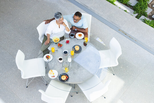 Senior biracial couple enjoys breakfast outdoors, with copy space
