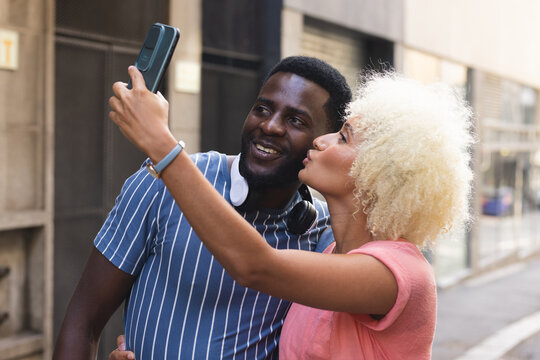 A diverse biracial couple takes a selfie outdoors in the city - Powered by Adobe