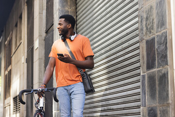 An African American man stands with his bike outdoors in the city, with copy space