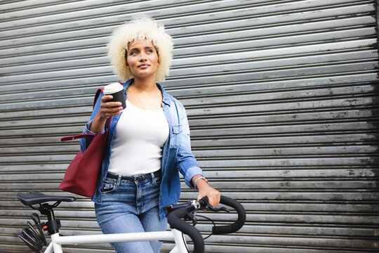 Young biracial woman enjoys a bike ride in the city, with copy space