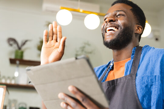 African American man waves cheerfully in a cafe setting