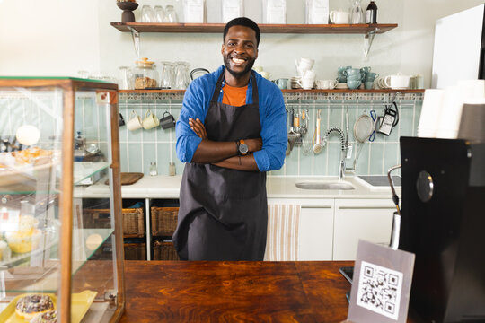 A cheerful African American man stands behind a cafe counter