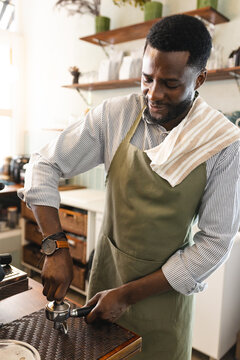 African American male barista prepares coffee at a cafe
