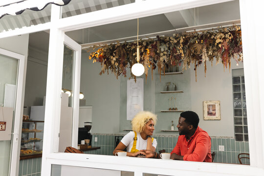 Young diverse biracial couple enjoy a conversation at a cozy cafe with copy space