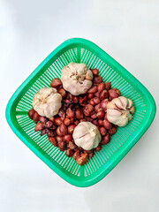 photo of onions and garlic in green tray on white background