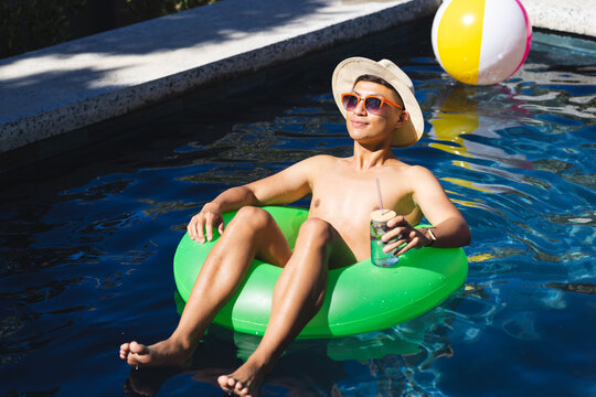 Young Asian man relaxes on a pool float