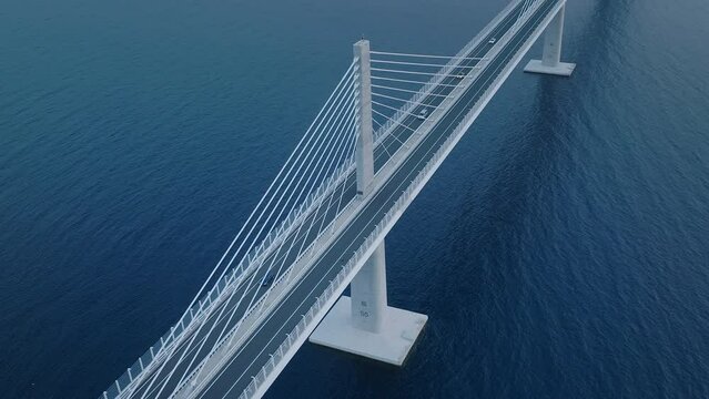 Cars crossing the bridge over the calm blue sea. The bridge across the blue Mediterranean sea. Aerial view.