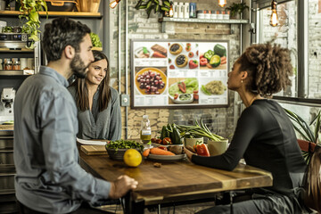 Inside a nutritionist's consultation room, a couple discusses their meal plan, board showcases vibrant food photos and nutritional charts.