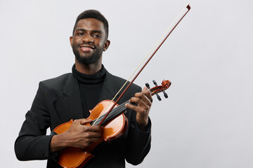 Professional African American musician in formal suit holding violin against white background for...