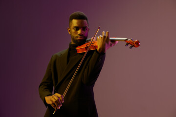 Elegant man in suit playing violin against vibrant purple background, creating a harmonious and...
