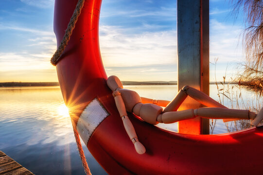 Lustiges Foto einer Holzpuppe beim Entspannen am See im Sonnenuntergang