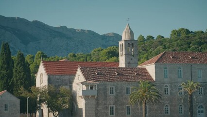 Franciscan monastery with Mediterranean architecture and red rooftop on an island. Close-up shot of monastery bell tower.