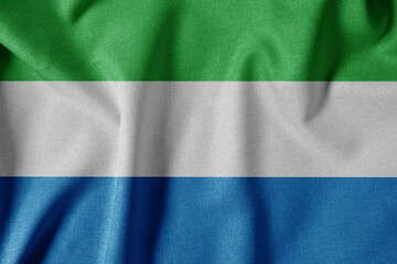 National Flag on Textured Fabric Background. Silk textured flag, realistic wave and flag look. SL  Flag of Sierra Leone