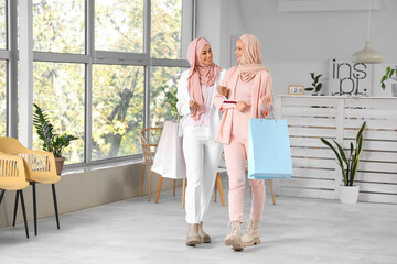 Beautiful young Muslim women in hijab with shopping bags at office