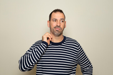 Bearded man in his 40s scratching highlighted with red collar on beige studio background, copy...