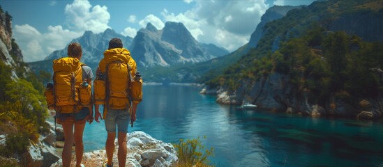 Couple with backpacks admiring lake from mountain top in natural landscape