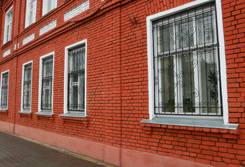 Beautiful red brick facade windows with wrought iron ornate grilles.
