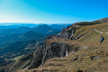 Fototapeta na wymiar Hiker Woman on edge of steep cliff on top of mountain peak Hohe Veitsch, Mürzsteg Alps, Styria, Austria. Idyllic hiking trail alpine terrain. Wanderlust remote Austrian Alps in autumn. Rock formation