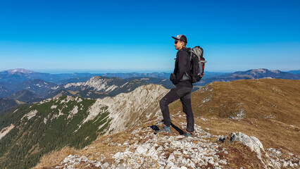 Obraz premium Hiker man on edge of steep cliff on top of mountain peak Hohe Veitsch, Mürzsteg Alps, Styria, Austria. Idyllic hiking trail in alpine terrain. Wanderlust remote Austrian Alps in autumn. Rock formation