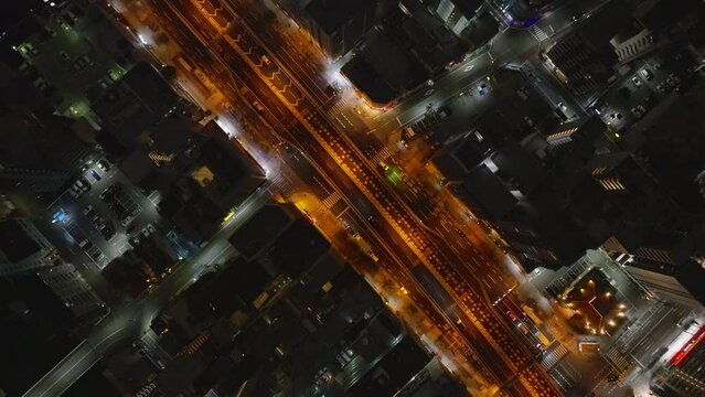 Birds eye shot of streets and buildings in urban borough in night city. Orange color streetlights along thoroughfare. Osaka, Japan