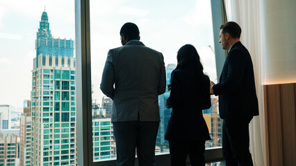Back view diverse team of ambitious business people standing in ornamented office gazing out window...