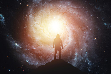 Silhouette of a man standing on the top of a mountain against the background of the galaxy....