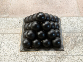 Pile of black color well preserved cannon balls. Old time warfare craft. Cost of war and materials for destruction and conquest. Military equipment and supply theme.