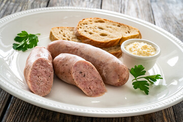 Easter breakfast - boiled white sausages, toasts and horseradish on wooden table 
