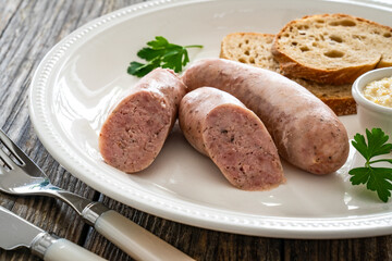 Easter breakfast - boiled white sausages, toasts and horseradish on wooden table 

