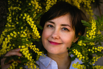 close up portrait of middle aged woman sitting under mimosa tree looking at camera