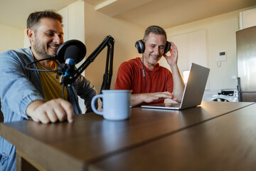 Men recording live podcast with headphones, microphone and laptop