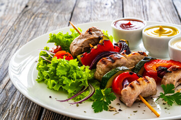 Meat skewers - grilled meat with vegetables on wooden background
