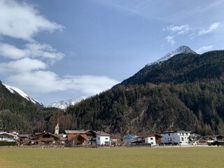 Fototapeta na wymiar Gemeinde Längenfeld am Hausberg Gamskogel im Ötztal / Tirol in Österreich - im Hintergrund Wald und die Schneeberge