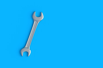 Spanner on blue background. Metal wrench in workshop. Repair and maintenance tool. Top view. Copy space. 3d render