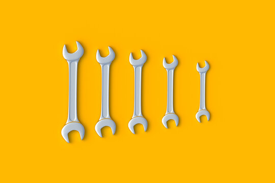 Row of wrenches of different sizes on orange background. Metal spanner in workshop. Repair and maintenance tool. 3d render