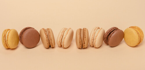 Chocolate macarons on a beige background, dessert