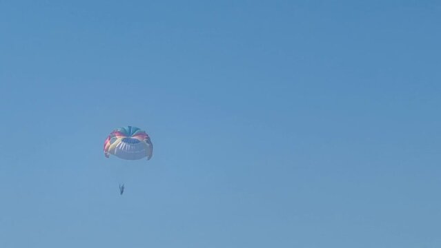 Parasailing above the sea, colourful parachute soaring in clear blue sky