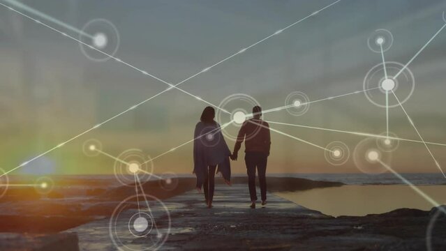 Animation of network of connections over caucasian couple walking on beach