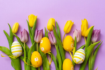 Easter eggs and yellow and purple tulip flowers, on a purple background. Easter, background