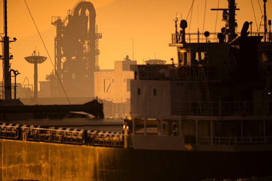 関門海峡で夕日を浴びて高炉の沖を通過する貨物船20240104-2