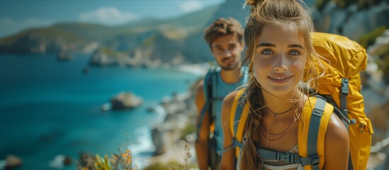 A happy couple with backpacks smile on a mountain top, enjoying leisure travel - obrazy, fototapety, plakaty